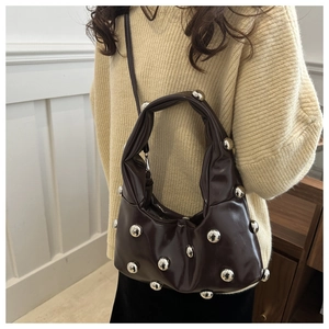 Detail of dark brown crescent hobo bag featuring silver metallic sphere studs and knot handle