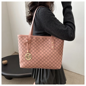 Pink monogram tote bag with gold M charm shown on shoulder for daily commute fashion