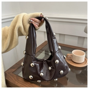 Detail of dark brown hobo bag with silver metallic sphere studs in a lifestyle setting