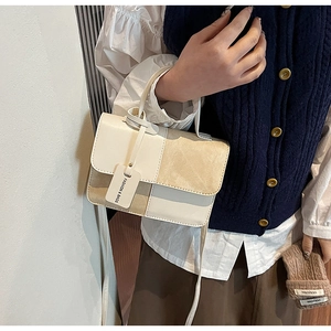 Close-up of contrast texture handbag featuring cream faux leather and khaki suede stitching