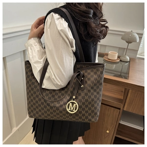 Detailed side view of large brown M-pattern tote bag showing ample capacity and leather strap