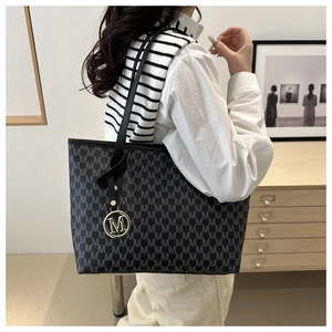 Detail view of large capacity tote bag with grey M pattern and gold metal pendant decoration