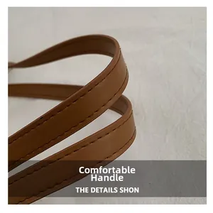 Detailed close-up of brown leather bag handles with fine stitching and smooth finish
