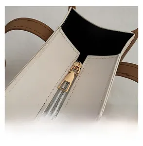 Detail of smooth gold zipper closure on minimalist cream and brown tote bag with stitching