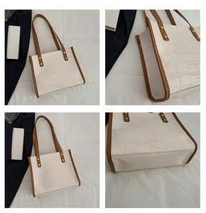 Detail view of white crocodile pattern tote bag with brown straps and golden rivets