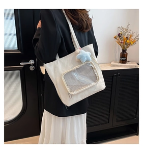 Detailed side view of white canvas tote bag with transparent front pocket and star pendant