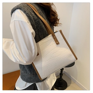 Detail of white crocodile pattern tote bag with brown straps worn on shoulder