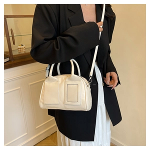 Sac Boston crème porté par un mannequin, détails de la texture cuir et des poignées