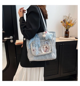 Detail of light blue embossed tote bag with transparent display pocket and plush star charm
