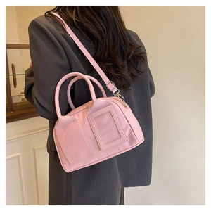 Sac Boston rose avec porte-carte porté sur un blazer gris pour un look élégant