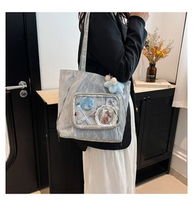 Detail of silver pleated nylon tote bag with transparent pocket for cartoon badges