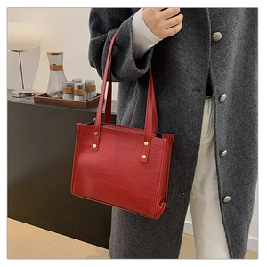 Detail of burgundy tote bag featuring premium crocodile embossed texture and gold rivets