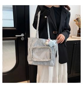 Detail of silver grey textured tote bag featuring a mesh front pocket and star charm