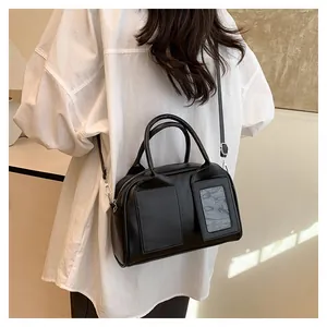 Detail of black Boston bag featuring dual handles and a transparent card slot pocket