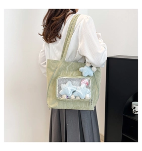 Detail of light green ita bag featuring a clear PVC window with star plush toys