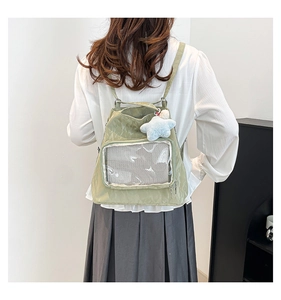 Detail of light green nylon backpack featuring a transparent mesh front pocket and star charm