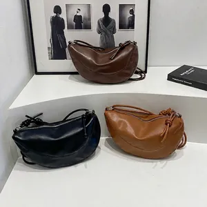 Sacs à bandoulière demi-lune en cuir marron, noir et beige sur supports blancs