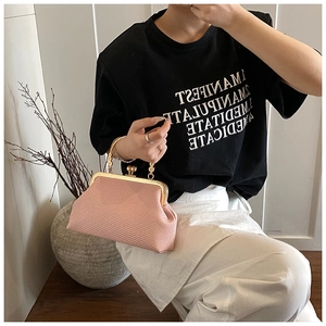 Détail du sac tressé rose avec fermoir doré vintage et poignée en métal sculpté
