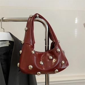 Deep red crescent underarm bag with silver rivet studs and a glossy finish