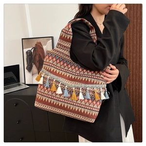 Dettaglio borsa a tracolla etnica con trame geometriche e nappe colorate in stile bohémien