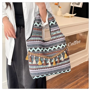 Dettaglio della borsa tote etnica con motivi geometrici colorati e nappe dorate