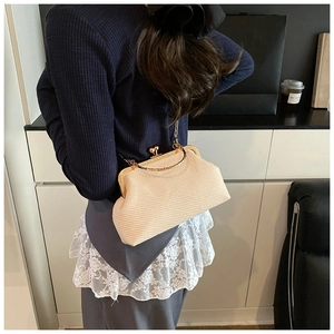 Détail d'un sac coquillage tissé beige avec fermoir en métal doré et bandoulière chaîne