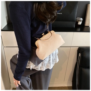 Vue détaillée du sac coquille beige plissé avec chaîne dorée sur mannequin en décor moderne