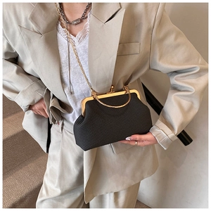 Detail of vintage black shell bag with golden kiss-lock closure and metal chain strap