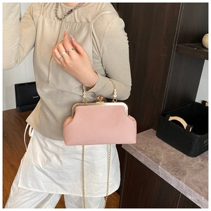 Détail d'un sac coquille tissé rose clair avec poignée dorée et fermoir boule