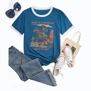 Flat lay of a blue ringer T-shirt with vintage cowboy print and western accessories