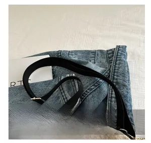 Dettaglio borsa a tracolla in denim blu con cinturino nero e fibbia in metallo