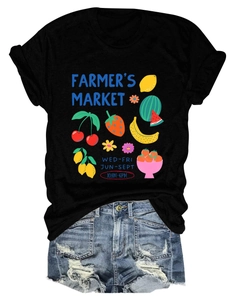 Detailed close-up of a black t-shirt featuring a colorful Farmer's Market fruit print design