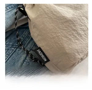 Dettaglio della borsa a secchiello beige con coulisse e trama in tessuto plissettato