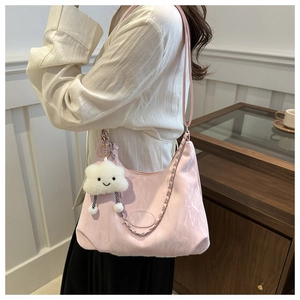 Detail of light pink pleated shoulder bag with silver chain and plush cloud charm