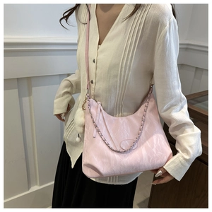 Dettaglio borsa a spalla rosa con catena argento, pompon bianco e texture marmorizzata