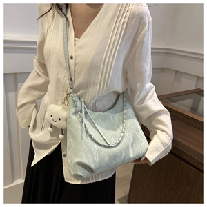 Detail of mint green tote with pleated leather texture, silver chain and plush charm