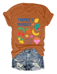 Flat lay of ginger orange t-shirt with fruit market print and ripped denim shorts