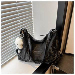 Detailed texture of black pleated PU leather tote bag with a cute white plush bear charm
