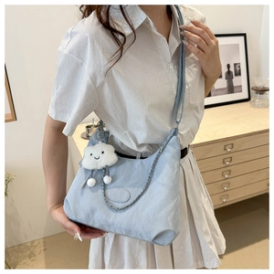 Light blue minimalist crossbody bag with cloud charm and chain strap shown on model