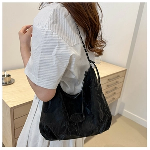 Detail of black wrinkled texture tote bag with leather and silver chain strap for women