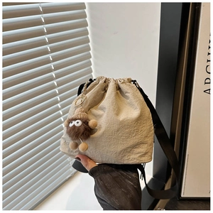 Dettaglio della borsa a secchiello beige in nylon con coulisse e ciondolo a mostro