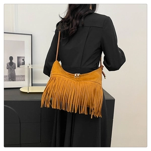 Vue détaillée du sac à bandoulière jaune gingembre à franges porté sur une robe noire
