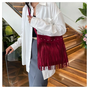 Detail of burgundy fringe shoulder bag showing suede texture and silver metal eyelets