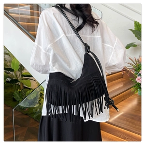 Vue détaillée d'un sac hobo noir en daim avec de longues franges et bandoulière à nœud