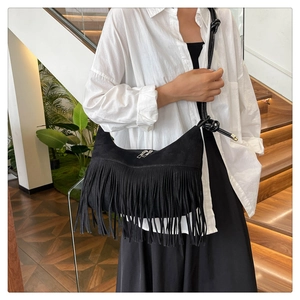 Détail du sac à bandoulière en daim noir avec franges, bandoulière nouée et accents métal