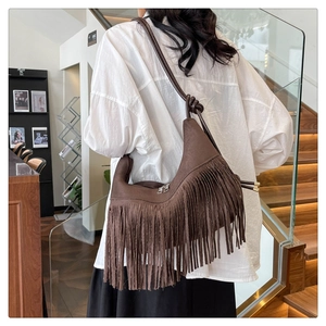 Détail du sac hobo en daim marron foncé avec de longues franges et une bandoulière nouée