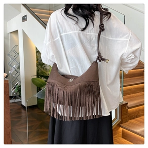 Détail du sac bohème en daim marron avec franges et bandoulière à nœuds décoratifs