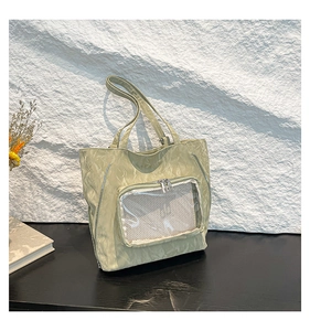 Detail of light green tote bag with pleated nylon texture and transparent mesh pocket
