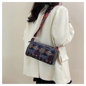 Sac bandoulière ethnique rayé avec large sangle porté sur une veste de tailleur blanche