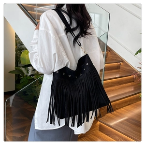 Detail of bohemian black suede tote bag with long fringes and silver metal eyelets